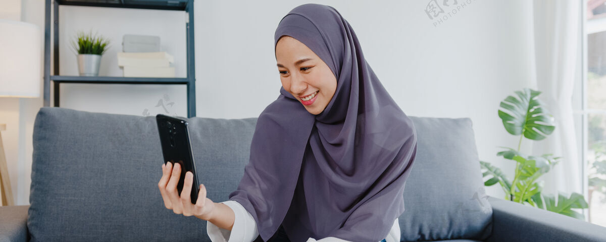 会议穆斯林女士戴着头巾 在家里用电话视频通话和夫妇交谈朋友虚拟手机