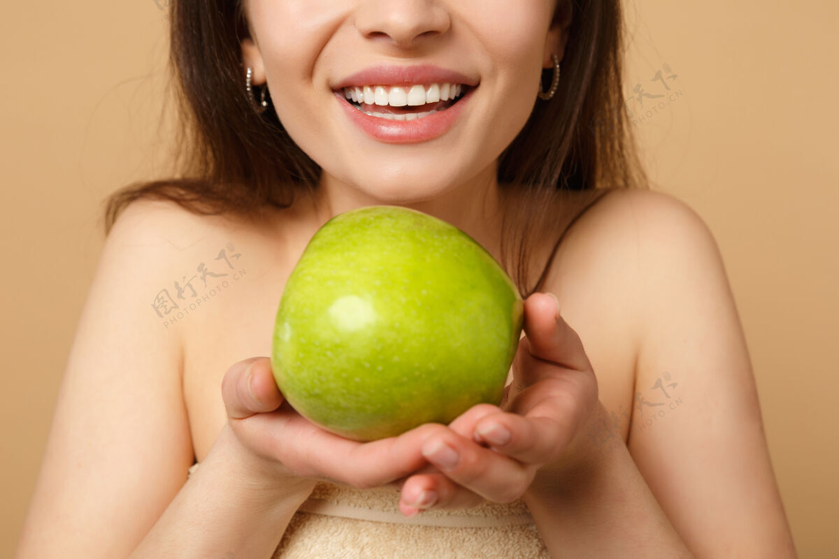 年轻特写黑发半裸完美皮肤的女人 裸妆把苹果隔离在米色粉彩墙上食物健身体重