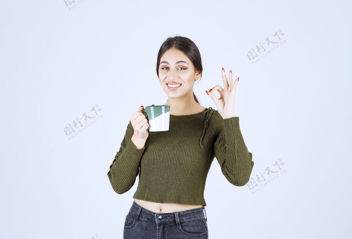 年轻的一个年轻微笑的女模特举着一个杯子 摆出一个很好的姿势人喝酒人