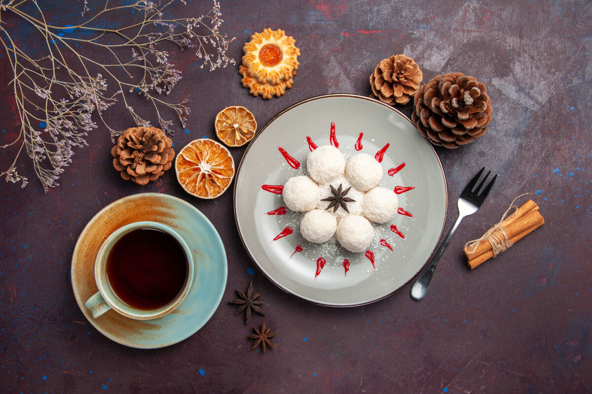盘子俯瞰美味的椰子糖小而圆的形成与一杯茶在一个黑暗的背景椰子糖茶甜饼饼干用餐圆形茶