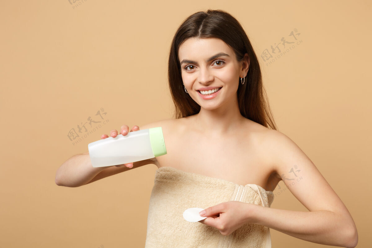 光滑特写黑发半裸完美皮肤的女人 去除隔离在米色粉彩墙上的裸妆卫生垫健康