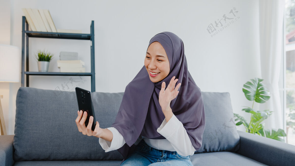住宅穆斯林女士戴着头巾 在家里用电话视频通话和夫妇交谈视频通话青少年阿拉伯语