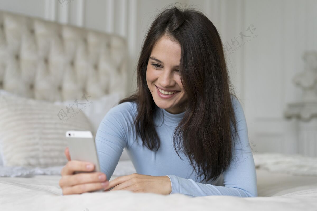 年轻人躺在床上用智能手机打视频电话的女人科技房子女性