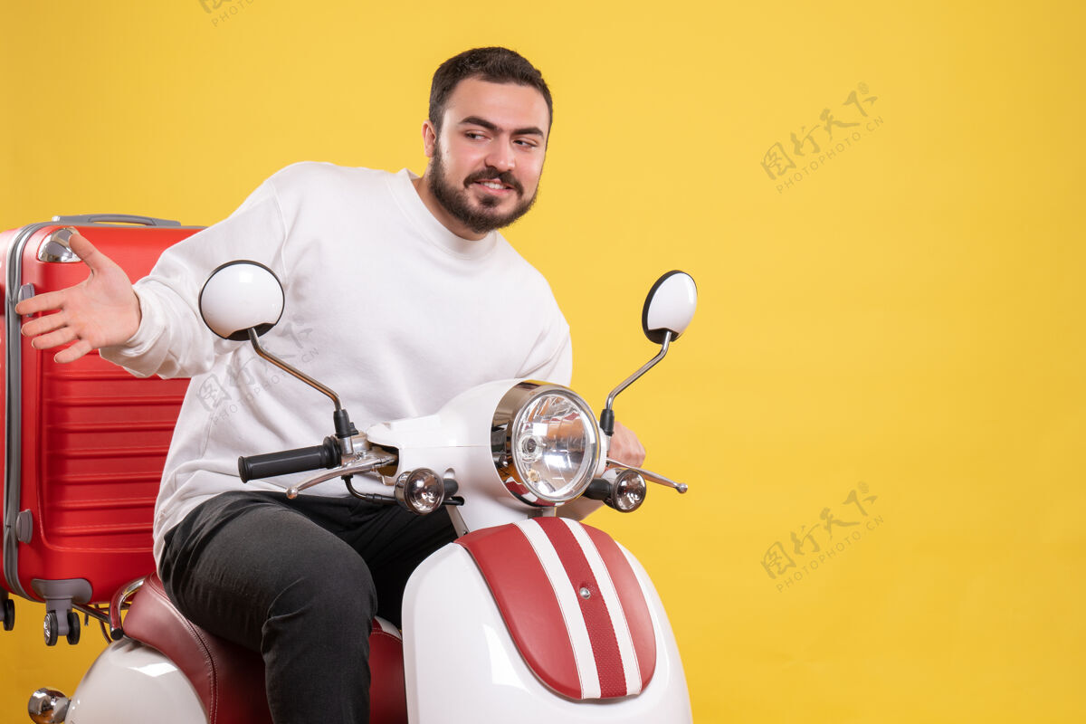 男性顶视图好奇的年轻人坐在摩托车上 手提箱放在孤立的黄色背景上摩托车身体运动