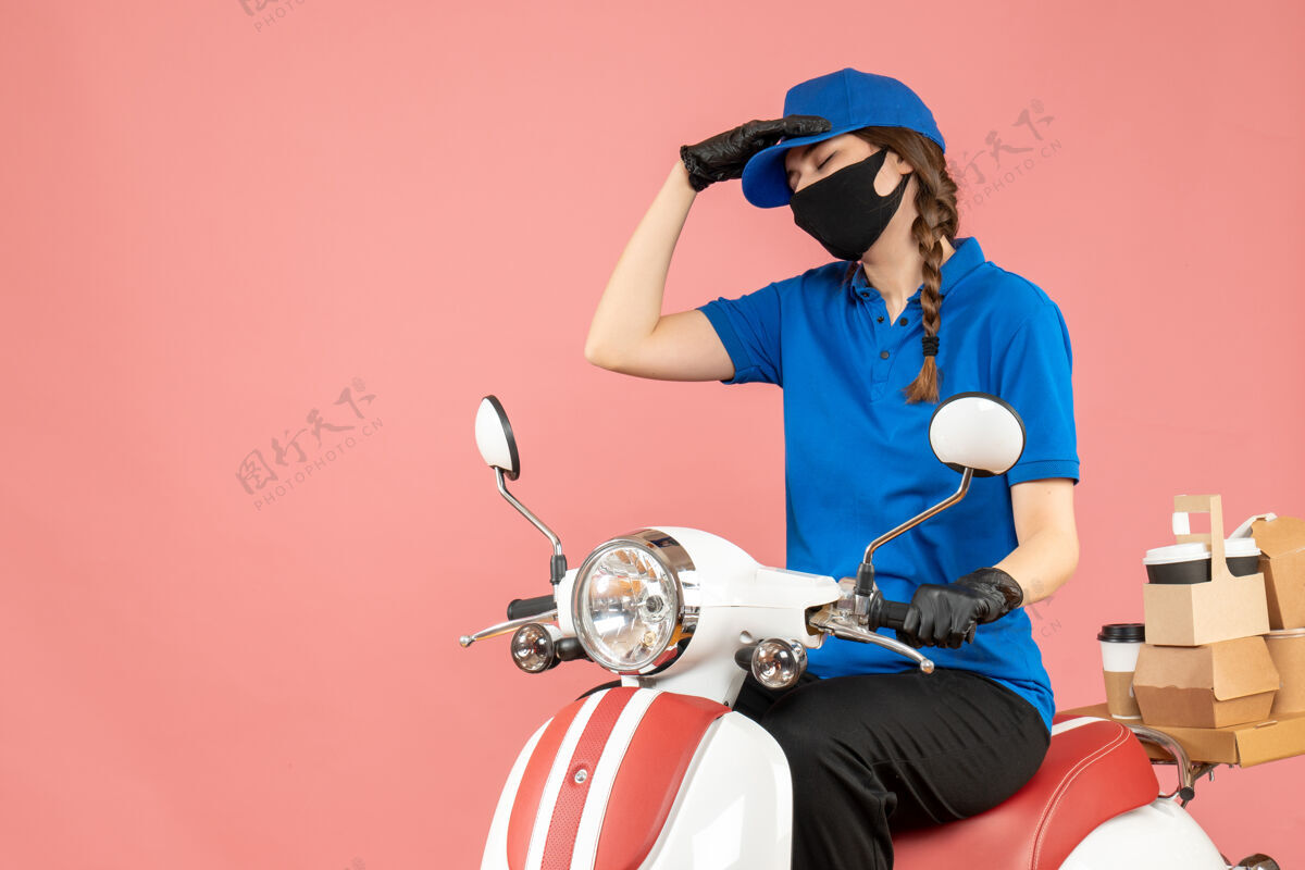 手套前视图疲惫的快递女孩戴着医用面罩和手套坐在滑板车上传递粉彩桃背景的命令疲惫人坐