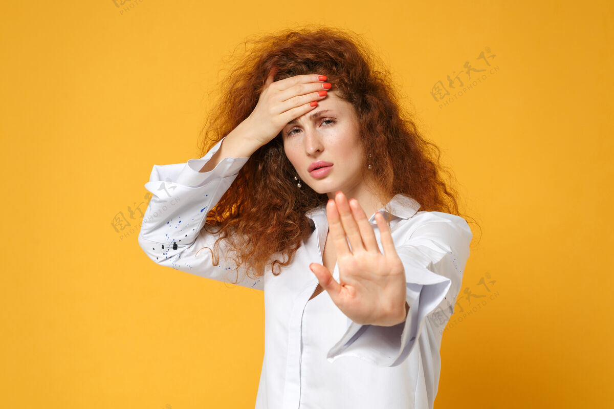 白种人疲惫的年轻红发女子穿着休闲白衬衫在黄橙色的墙上摆着孤立的姿势女孩一个疲倦