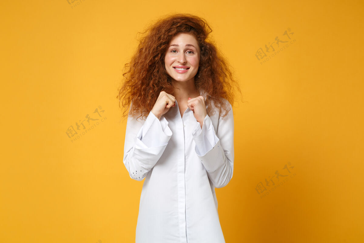 肖像快乐微笑的年轻红发女子女孩在休闲白衬衫摆出孤立的黄橙色墙上时尚手势白种人