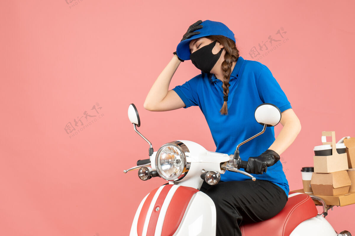 累顶视图疲惫的快递女孩戴着医用口罩和手套坐在滑板车上传递粉彩桃订单滑板车视图车辆