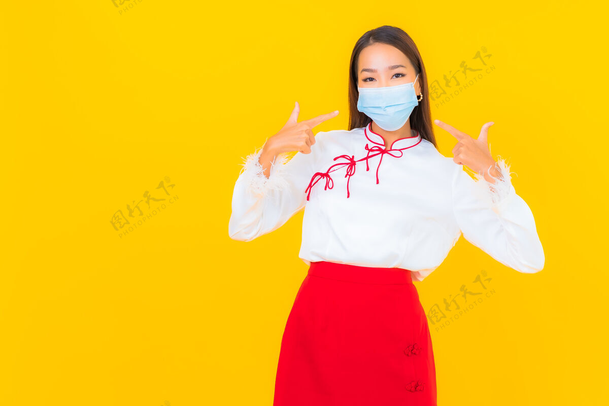 成人肖像美丽的亚洲年轻女子戴上口罩 用酒精凝胶保护黄色的covid19疾病电脑口罩