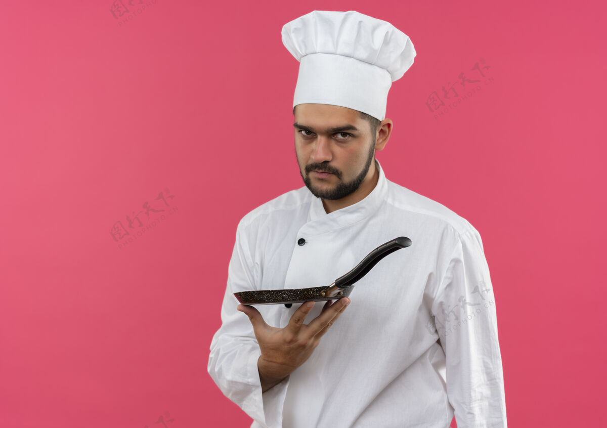 平底锅自信的年轻男性厨师身着厨师制服 手拿煎锅 隔离在粉色墙壁上 留有复印空间男性制服厨师