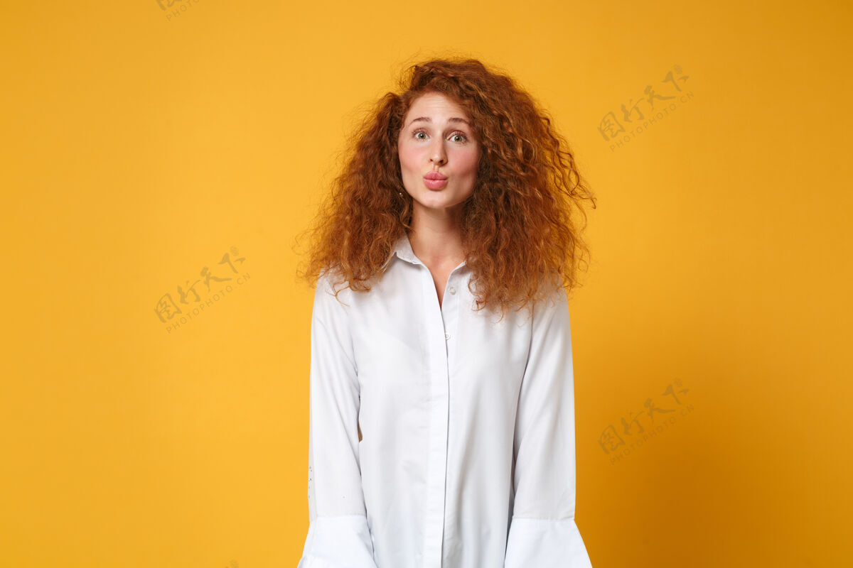 女人漂亮有趣的年轻红发女子女孩在休闲白衬衫摆出孤立的黄橙色墙上橙色白种人时尚
