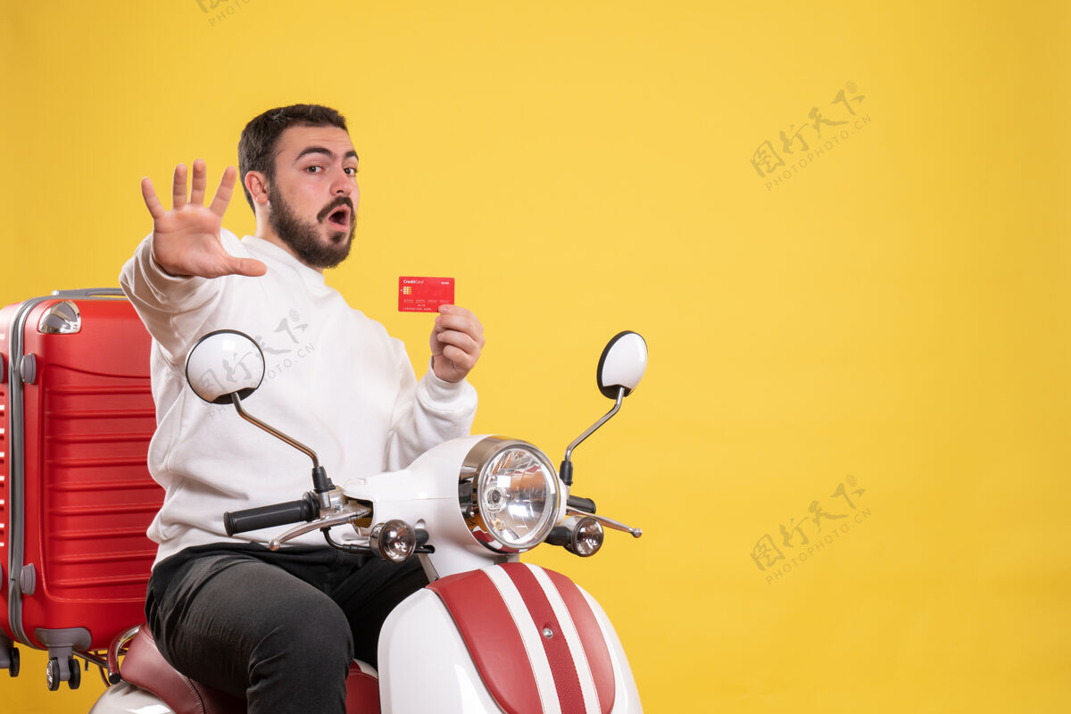 男人旅游旅游概念与年轻害怕旅行男子坐在摩托车上 手提箱上拿着黄色的银行卡运动摩托车年轻人