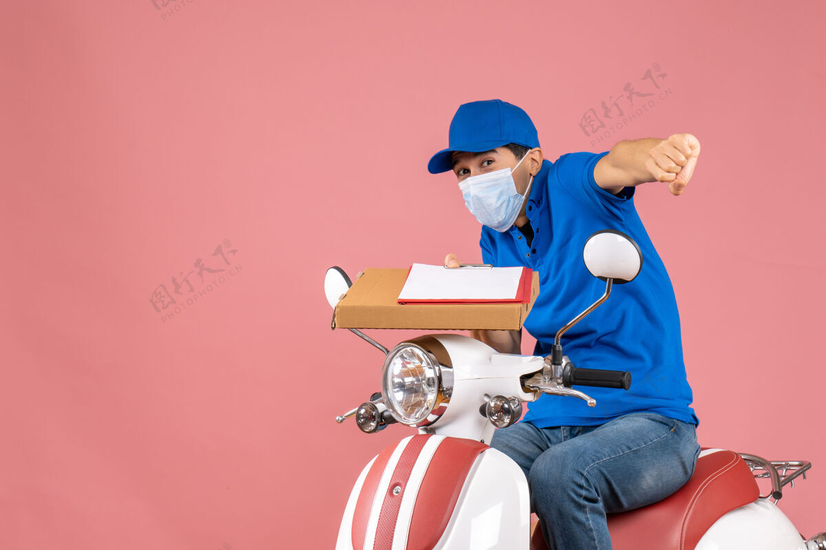 情绪顶视图疯狂情绪化的男性送货员戴着面具戴着帽子坐在滑板车上传递订单手持桃色背景文件抱着头盔足球头盔