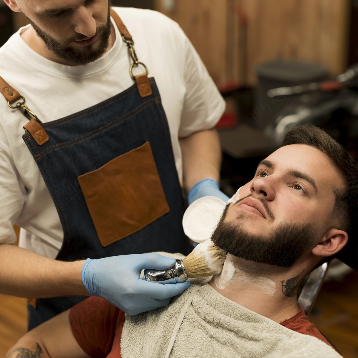 剃须泡沫理发师用剃须膏勾勒男顾客的胡须轮廓男人广场职业