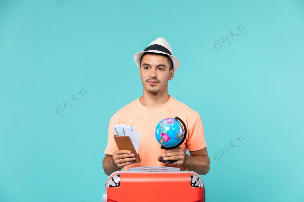 地球仪正面图男性在度假时拿着小地球仪和蓝色的门票举行假期旅行