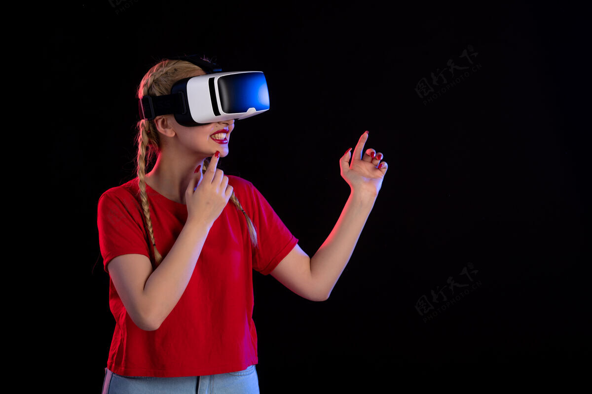 女士年轻女性在黑暗的墙上玩虚拟现实的正面图成人正面视图