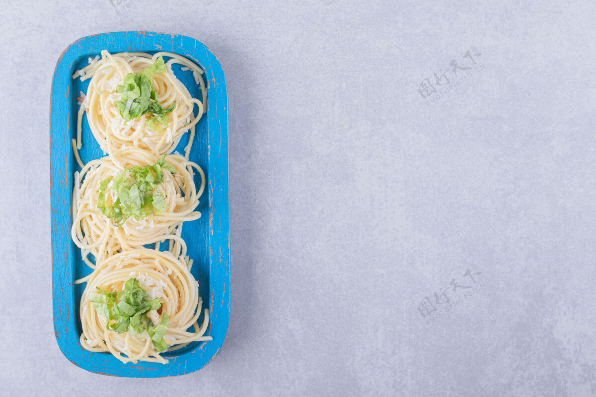 晚餐美味的煮意大利面 蓝色盘子上有绿色蔬菜生菜烹饪一餐