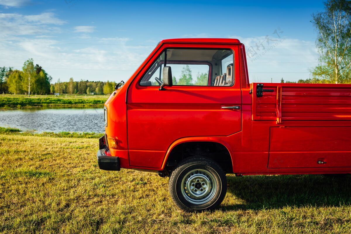 速度一辆红色卡车在水边的绿地上的特写镜头驾驶土地田地
