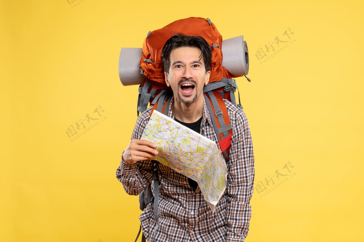 校园正面图年轻男性带着背包徒步旅行黄色背景上拿着地图公司旅行空气自然校园森林色彩旅行举行徒步旅行