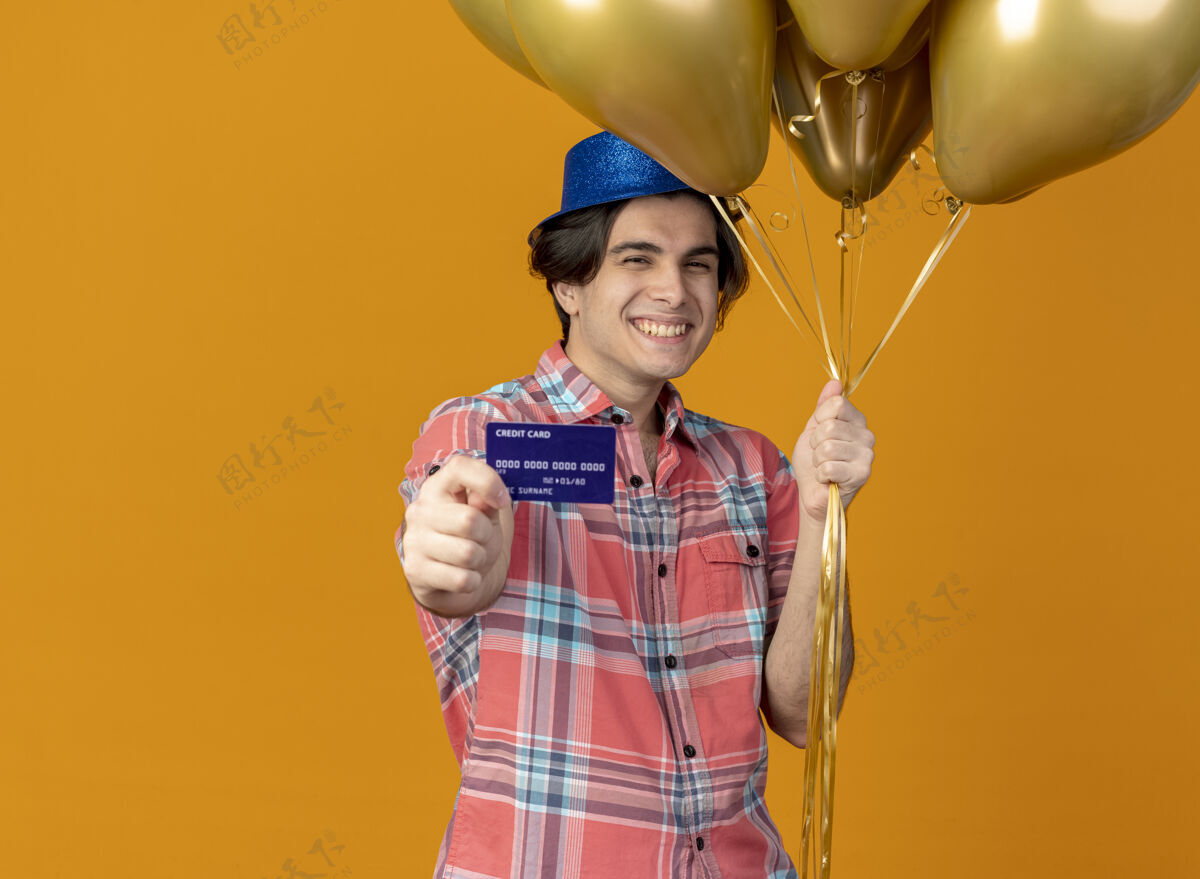 男人面带微笑的白人帅哥戴着蓝色派对帽手持氦气球和信用卡派对微笑复制