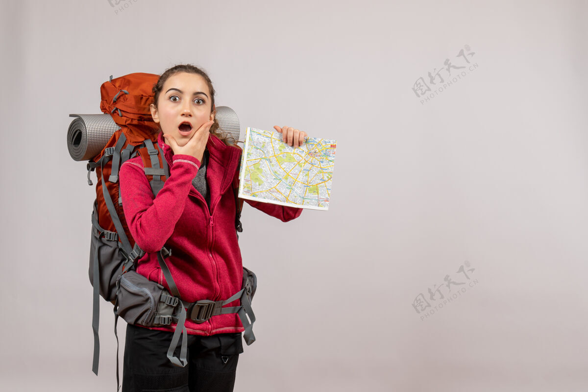 女士迷惑不解的年轻旅行者背着大背包 手里拿着灰色的地图大灰色地图