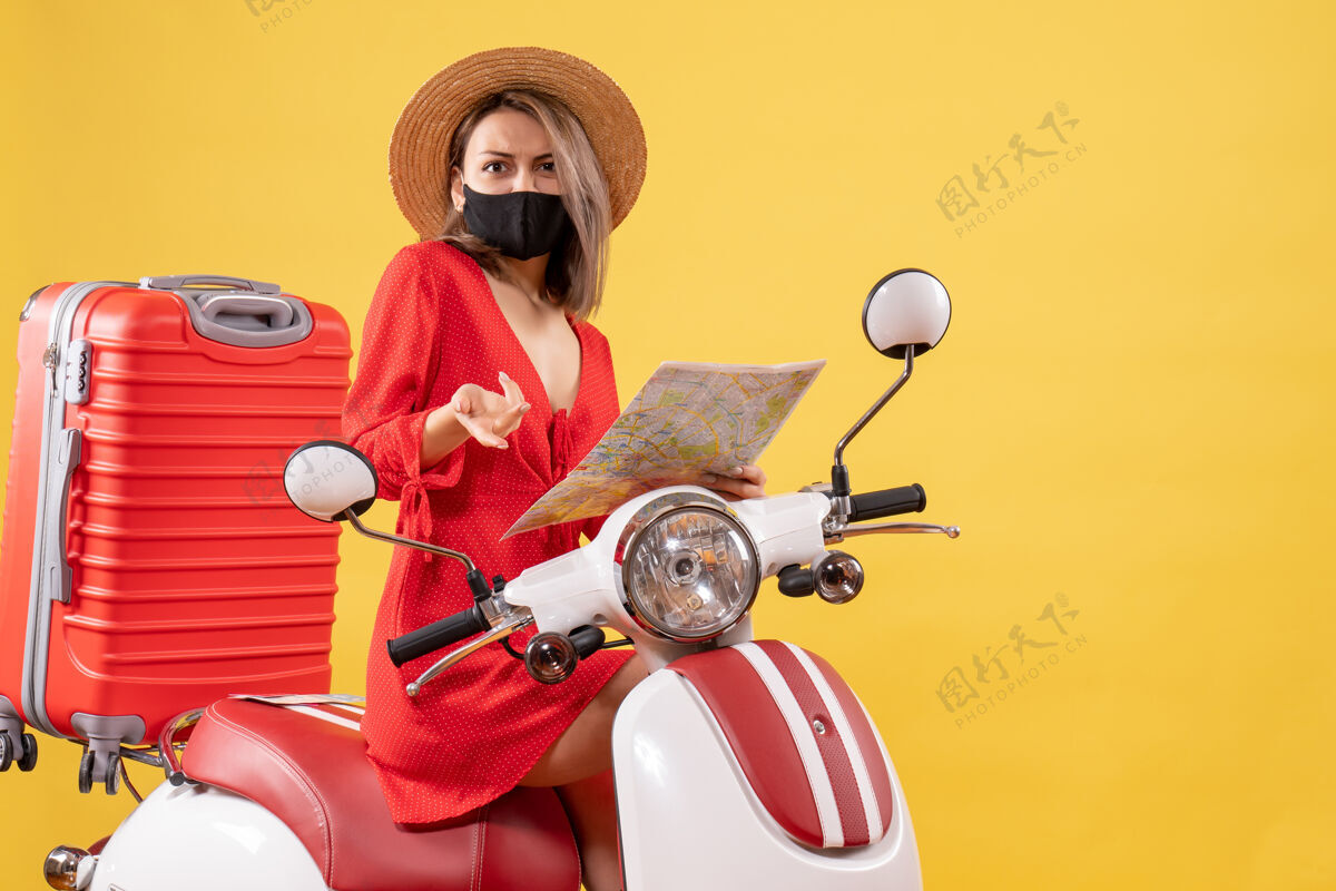 摩托车拿着地图 穿着红衣服的年轻女士困惑地站在轻便摩托车上驾驶衣服红色