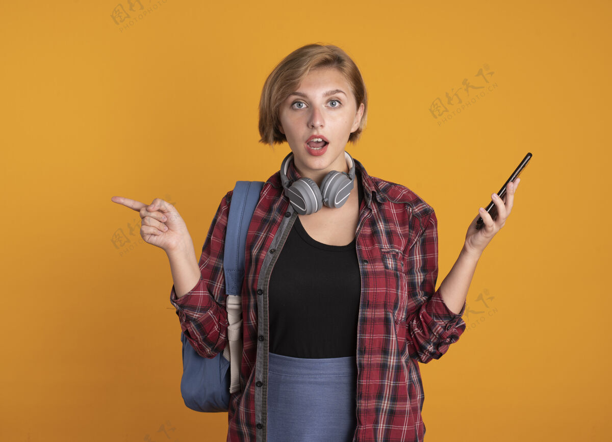 学生给人印象深刻的年轻斯拉夫女学生戴着耳机背着背包拿着电话指着身边耳机斯拉夫背包