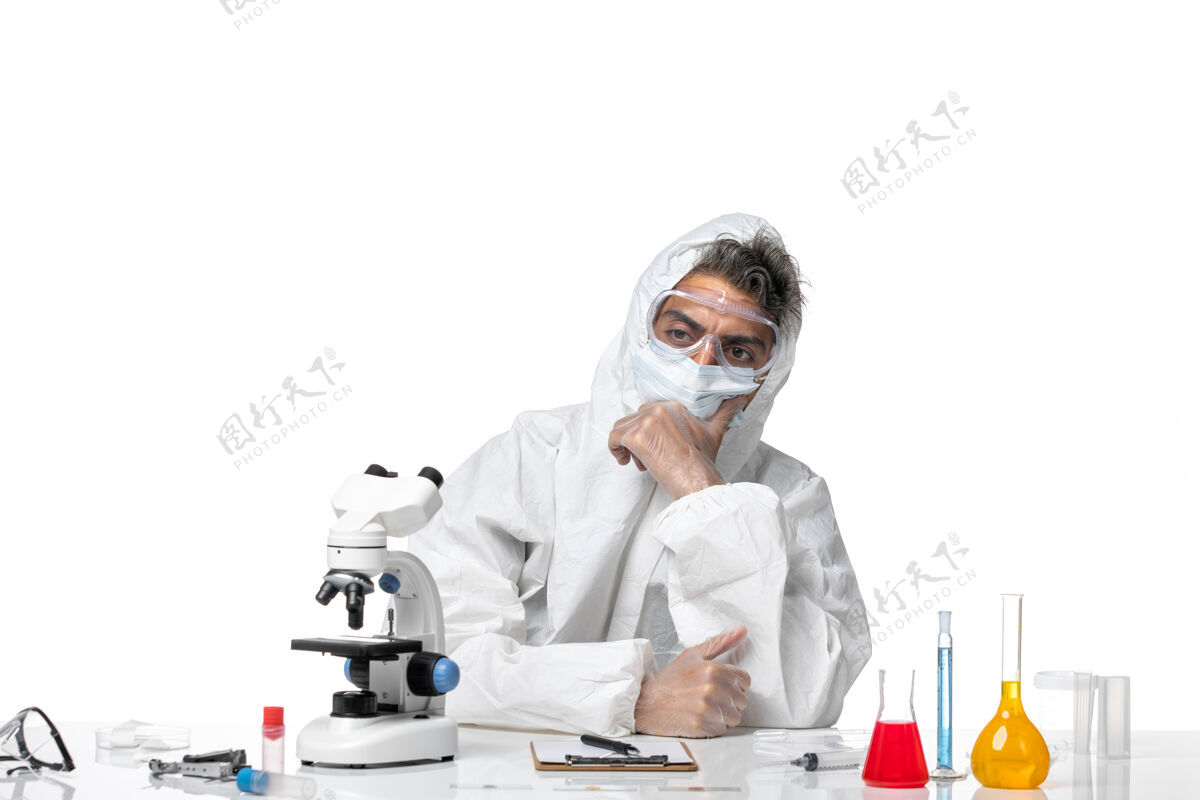 健康一个穿着防护服 戴着口罩的男医生正坐在白色的床上思考医学专业西装