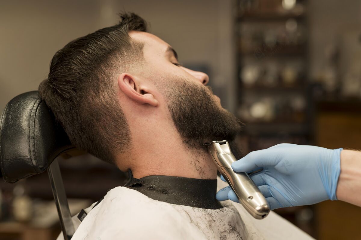 就业在理发店理胡子的年轻人理发师乳胶手套雇员