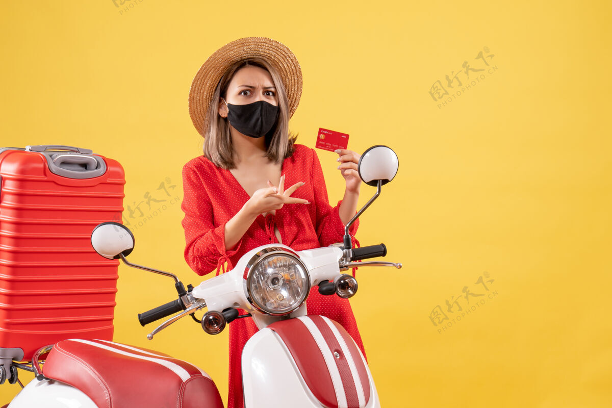 党戴着黑色面具的漂亮女人拿着信用卡在摩托车旁表情黑色摩托车