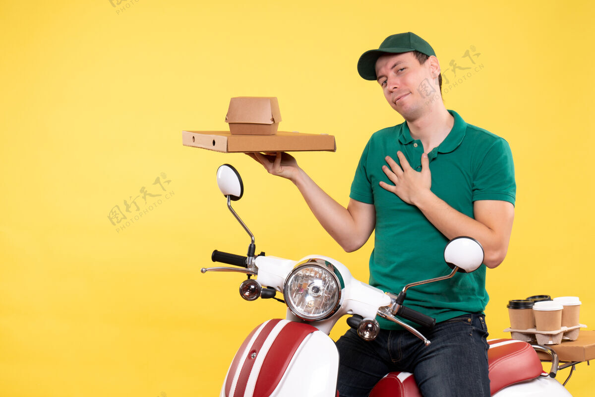 摩托车正面图身着制服的年轻男性快递员手持黄色食品包装食物年轻男性信使货箱
