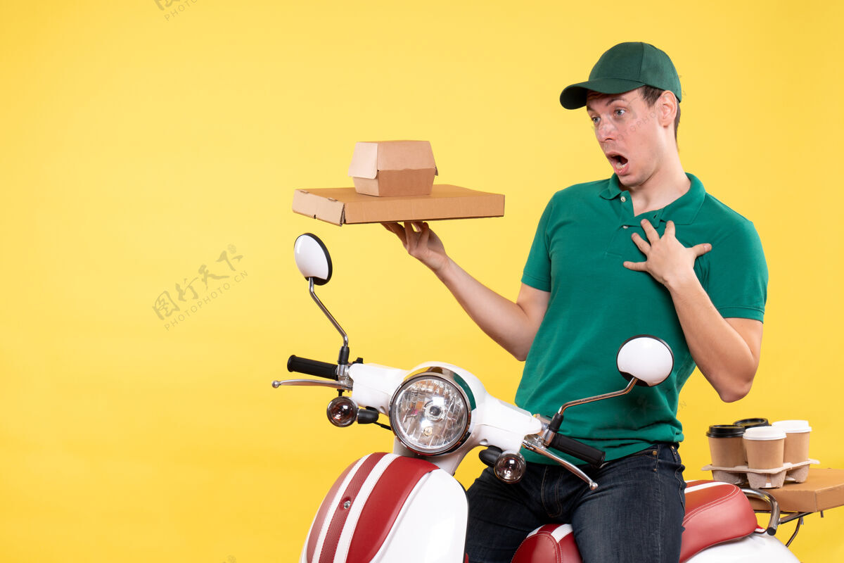 货箱正面图身着制服的年轻男性快递员手持黄色食品包装年轻男性信使人头盔