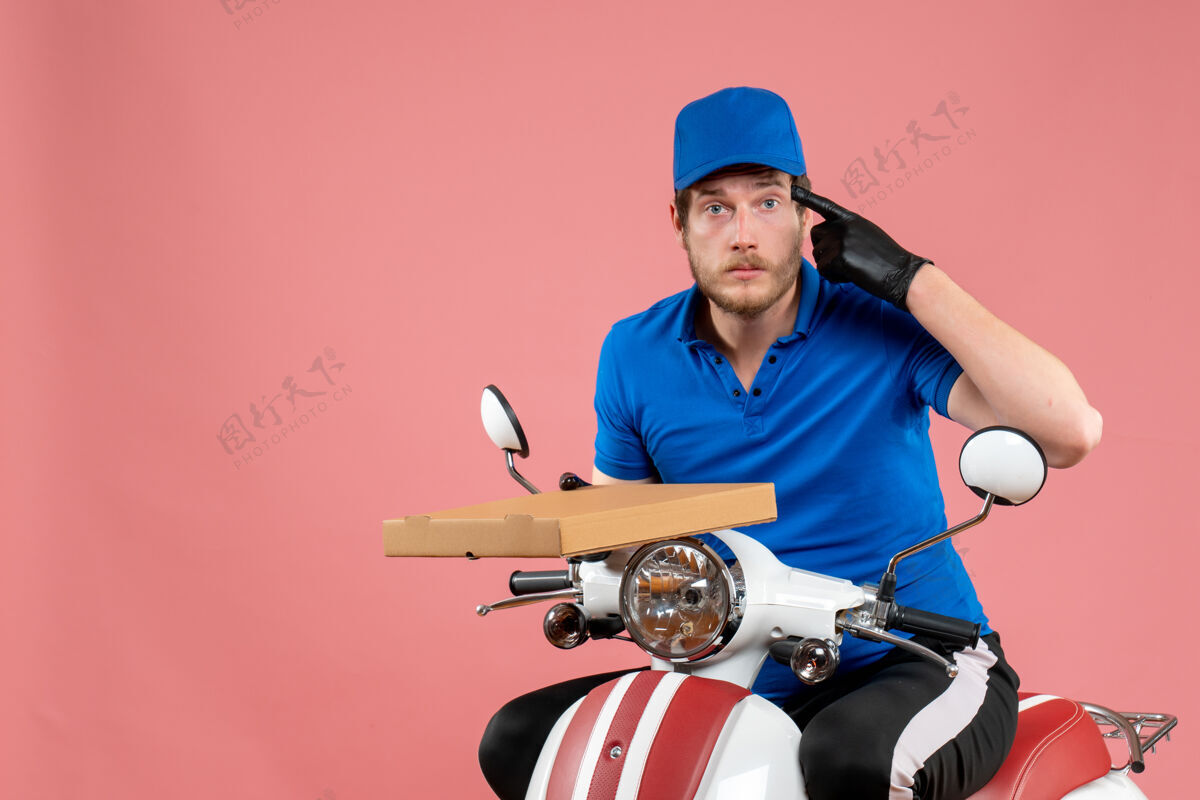 自行车正面图男性信使坐在自行车上 拿着粉红色的比萨饼盒头盔帽子盒子