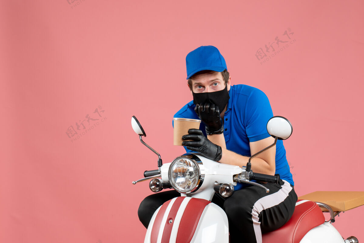 举行正面图男性信使坐在自行车上 拿着粉红色的咖啡男信使服务工人