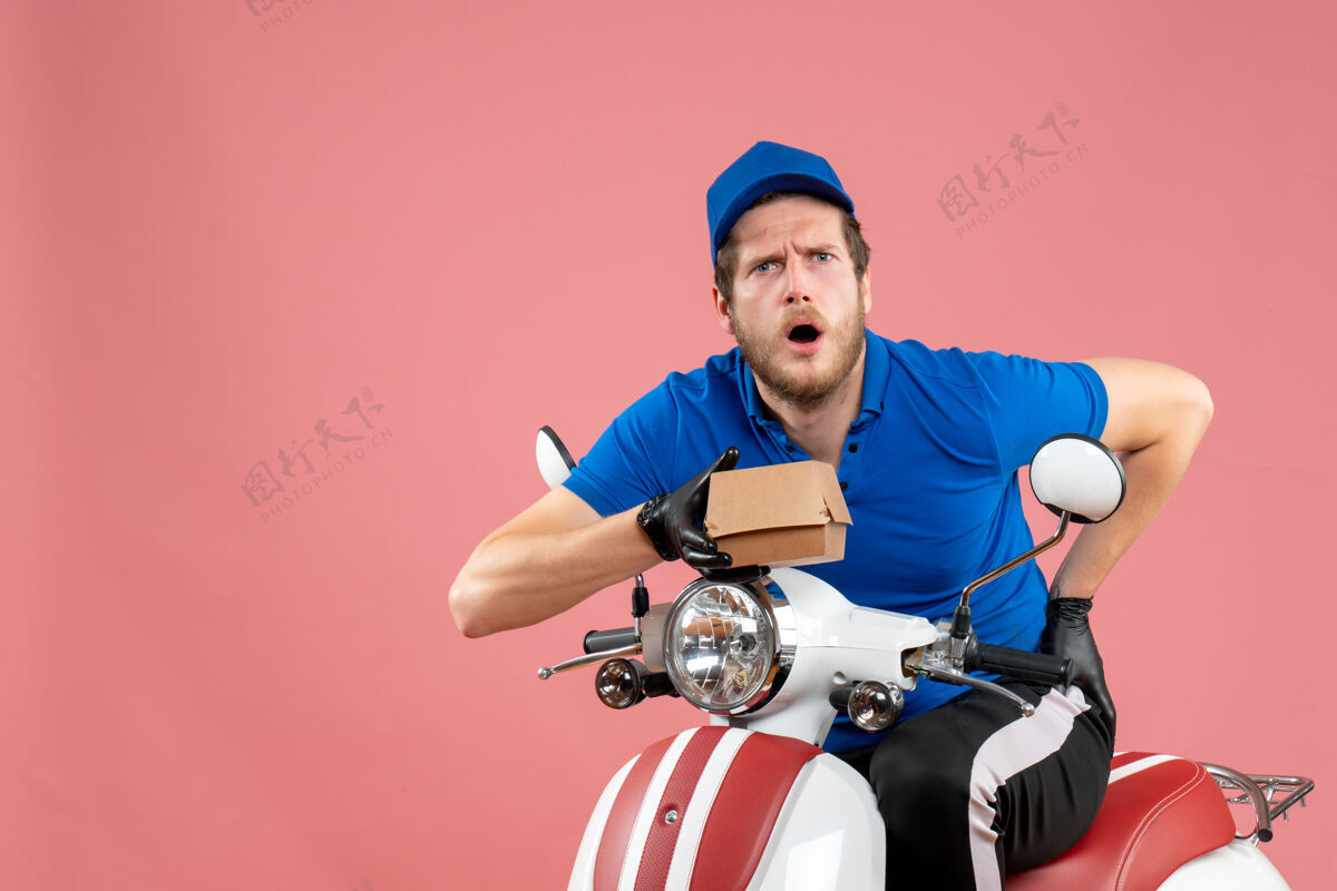 服务正面图男性信使坐在自行车上 拿着粉红色的小食品包包装工人自行车
