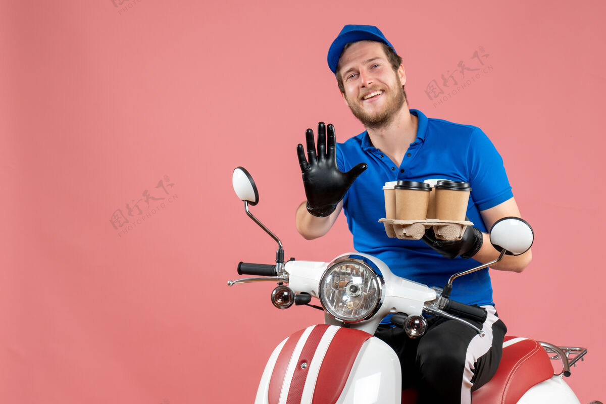 拿着正面图男性信使坐在自行车上拿着咖啡杯在粉红色工作人制服
