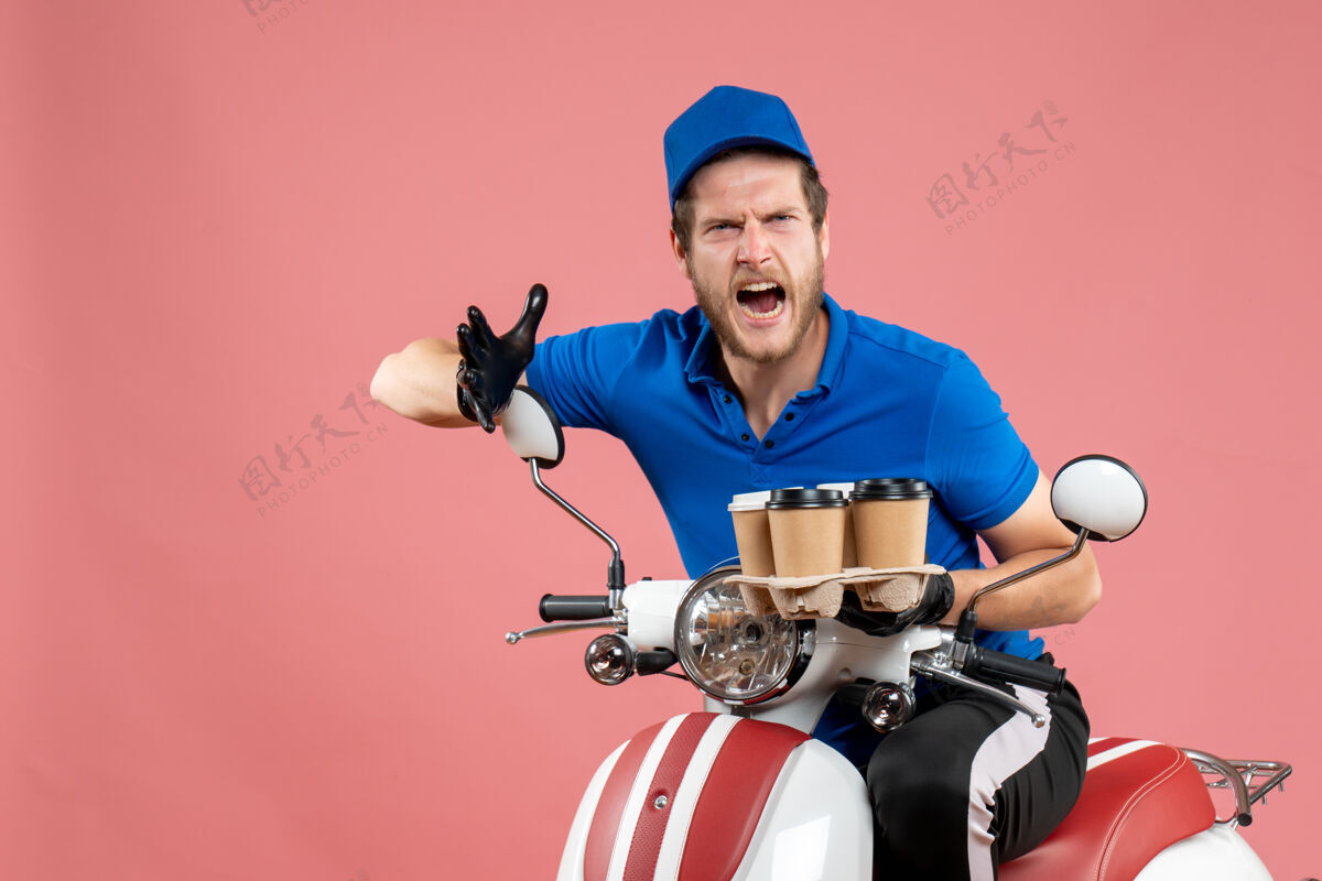 拿着正面图男性信使坐在自行车上拿着咖啡杯在粉红色送货人自行车