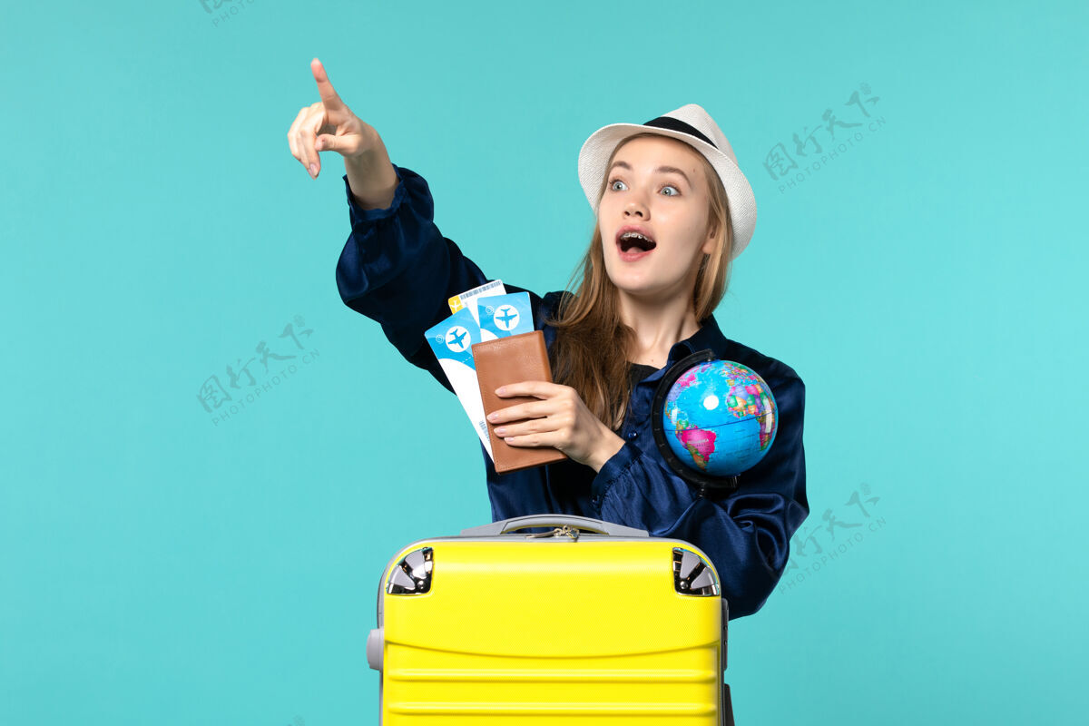地球仪正面图年轻女子手持机票和地球仪在蓝色背景的飞机上海上度假远航年轻女子人旅程
