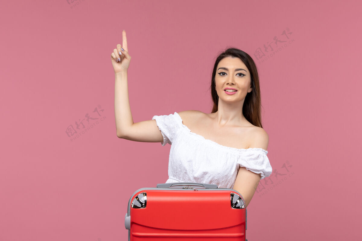 漂亮正面图：年轻女性带着她的红色袋子准备度假 背景是粉色的出国旅行 海上旅行包旅行旅行