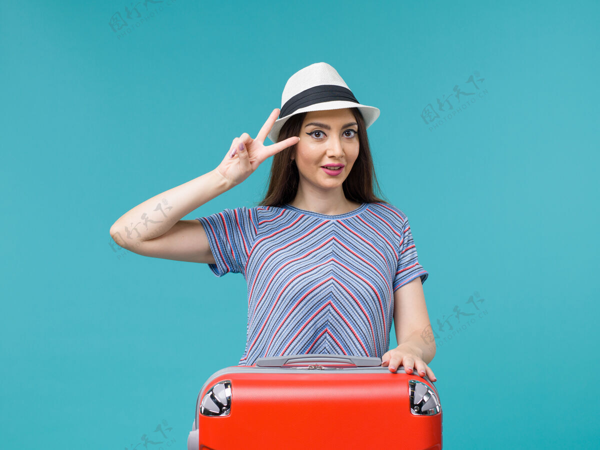 肖像前视图度假妇女与她的红色袋子享受她的蓝色背景旅行旅行旅行度假女性旅行人休闲包