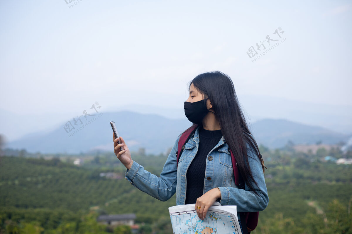 女人亚洲女游客戴着口罩看手机女孩地图预防