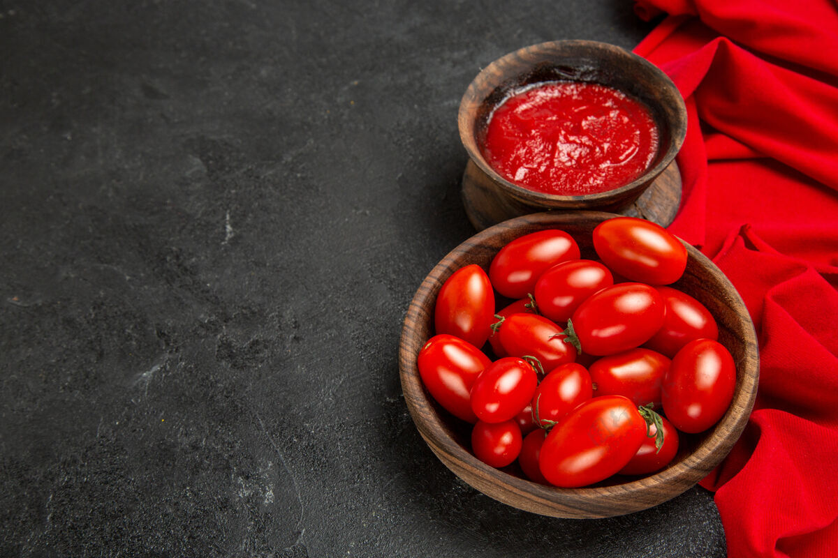 蔓越莓底视图碗与樱桃番茄和番茄酱红毛巾在黑暗的背景成熟健康毛巾