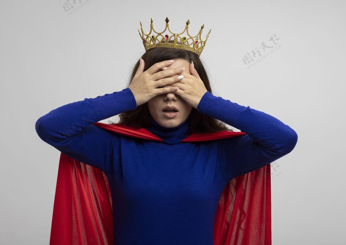 手焦急的白人超级英雄女孩戴着王冠 披着红色斗篷 双手捂着白色的眼睛斗篷王冠掩护