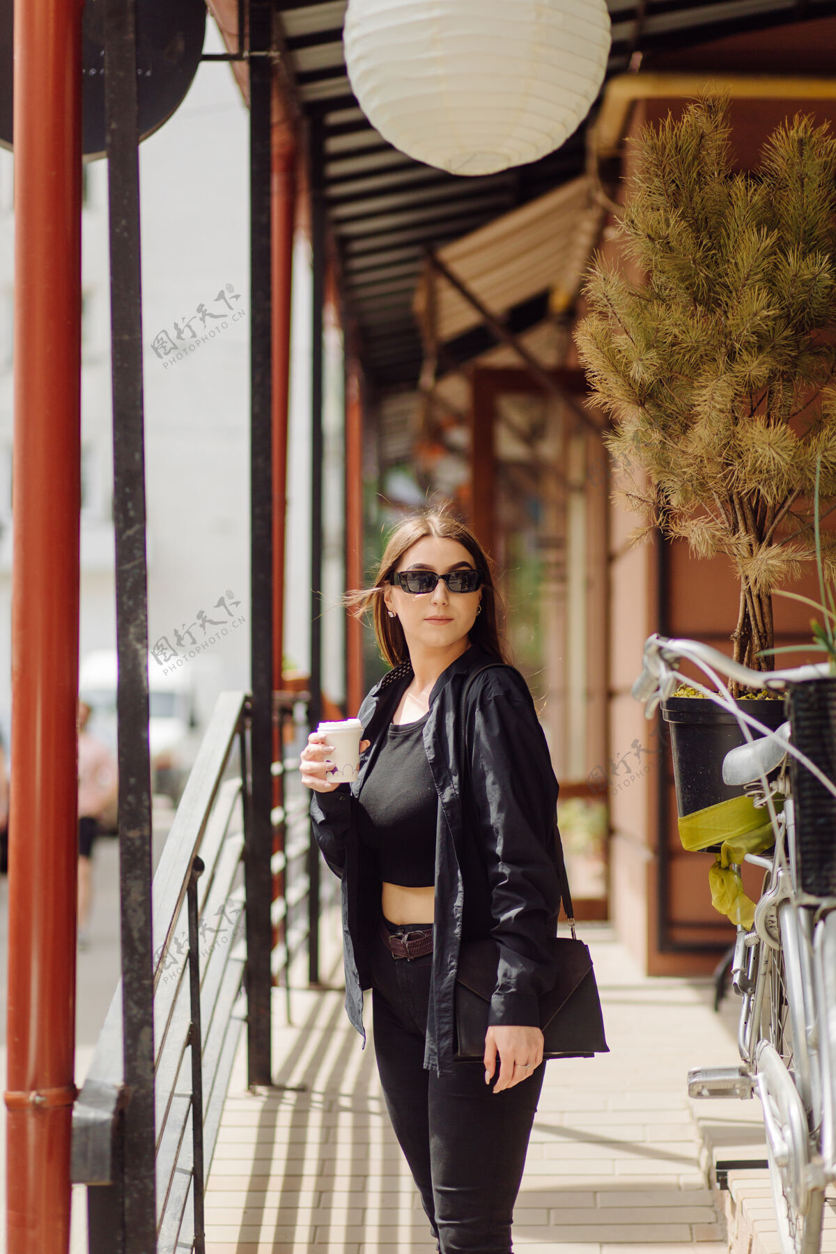 散步户外生活写真迷人的黑发女孩喝咖啡 走在城市街道上太阳镜咖啡馆女人
