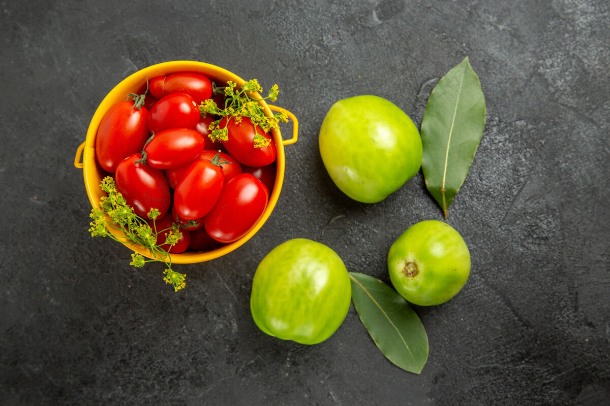 食物顶视图黄色的桶里装满了樱桃番茄和莳萝花 月桂叶和绿色的西红柿 在黑暗的地面上有复制空间生的叶子顶部