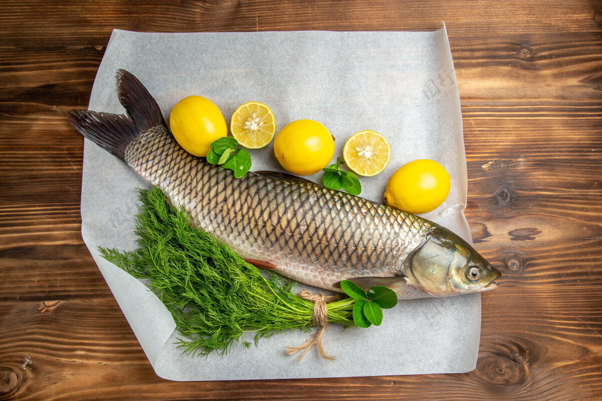 鲈鱼在棕色的桌子上俯瞰新鲜的柠檬和绿色的鱼海鲜健康棕色