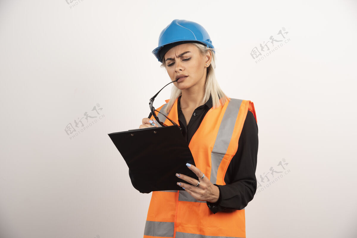 制服认真的女建设者头盔上看剪贴板高品质的照片建筑安全帽头盔