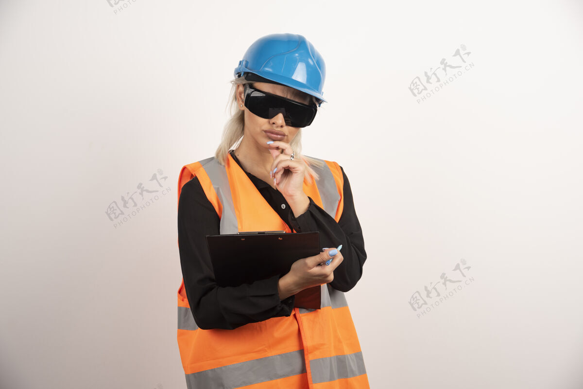 剪贴板戴眼镜的女工程师看着白色背景上的剪贴板高质量的照片人工程师工人