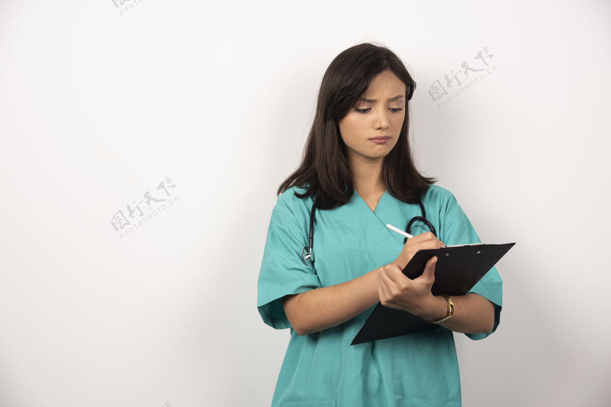 肖像女医生用听诊器在剪贴板上写字高质量的照片保健工人医生