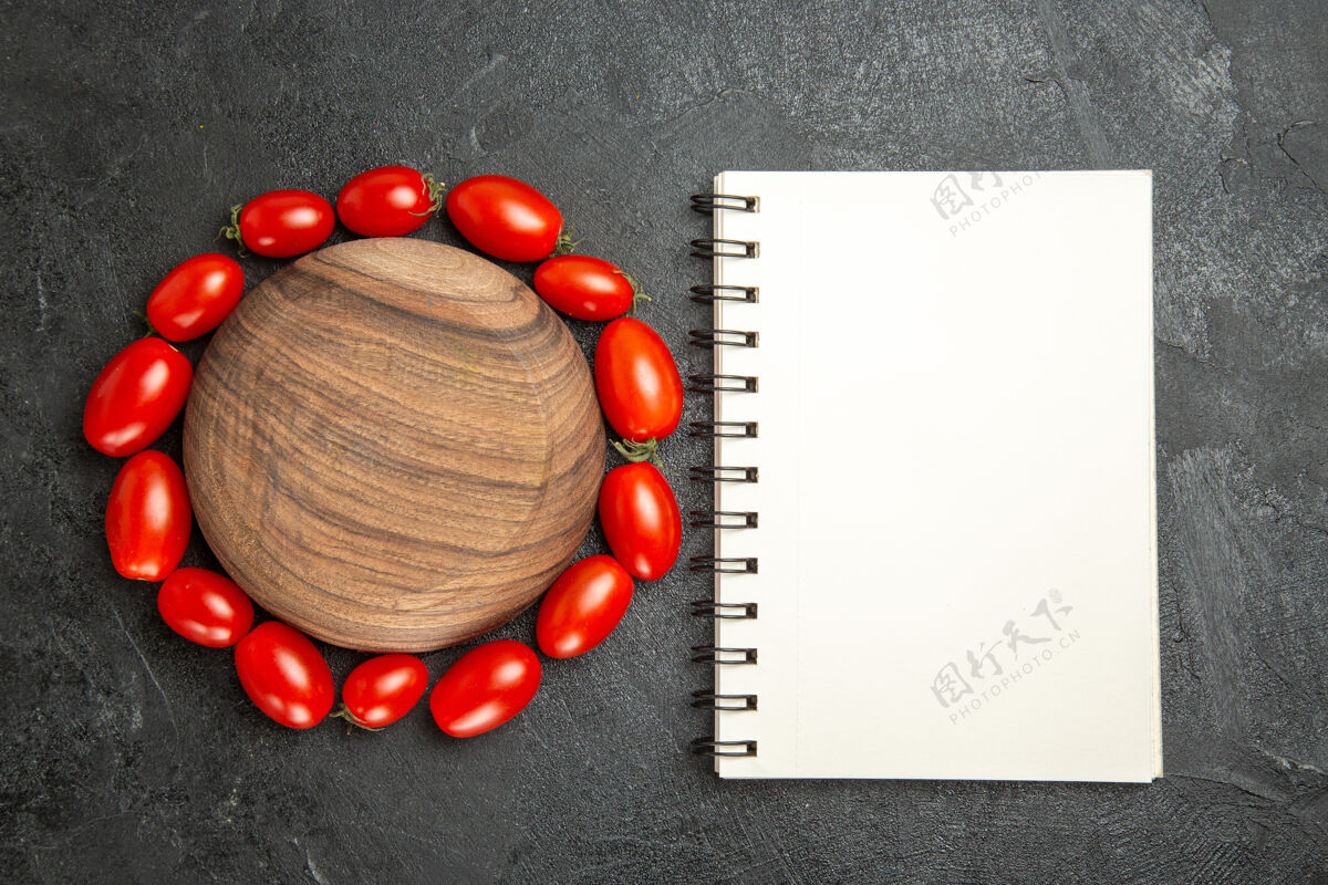 周围顶视图樱桃西红柿围绕一个木制盘子和一个笔记本在黑暗的地面上庆祝季节深色